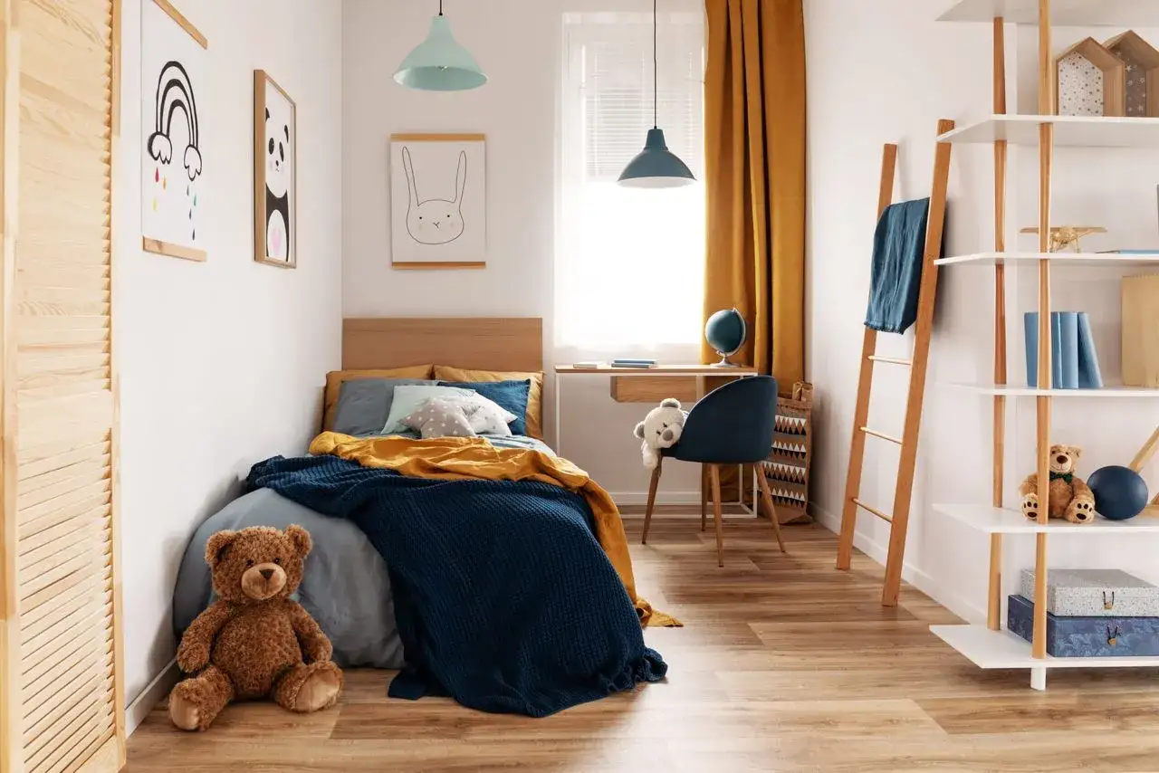 Chambre d'enfant douillette avec lit bleu et jaune, ours en peluche et affiches. Le chauffage de la chambre bébé est assuré par un radiateur discret.