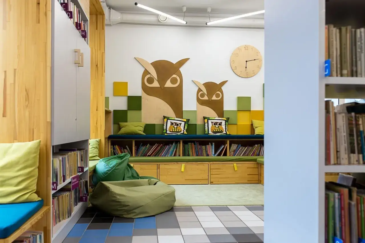 Przytulna biblioteka z sowami na ścianie. Tu poznasz zasady dystrybucji książek do bibliotek publicznych i szkolnych.
