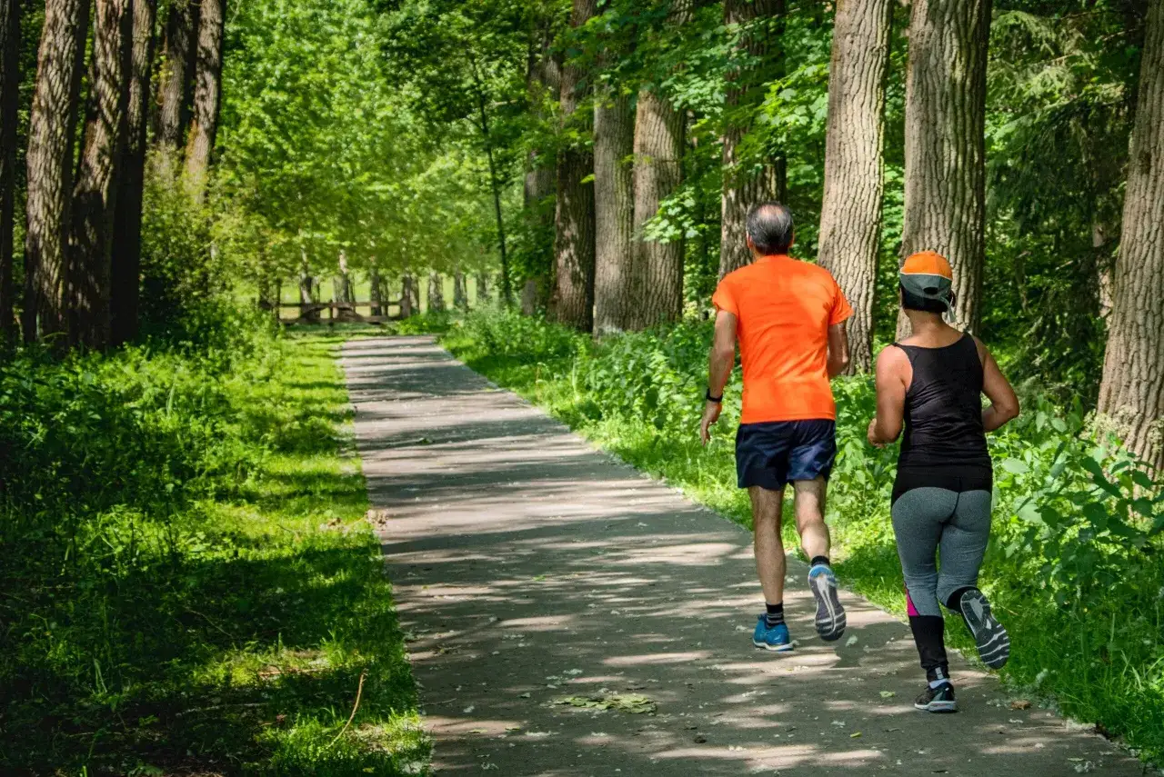 Coppia corre su sentiero nel bosco, un ottimo modo per iniziare il trail running.