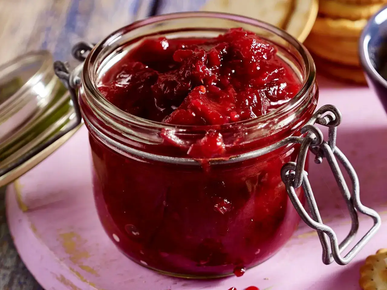 Ein Glas mit leuchtend rotem Zwetschgen-Chutney, bereit, zu Käse oder Gebäck serviert zu werden.