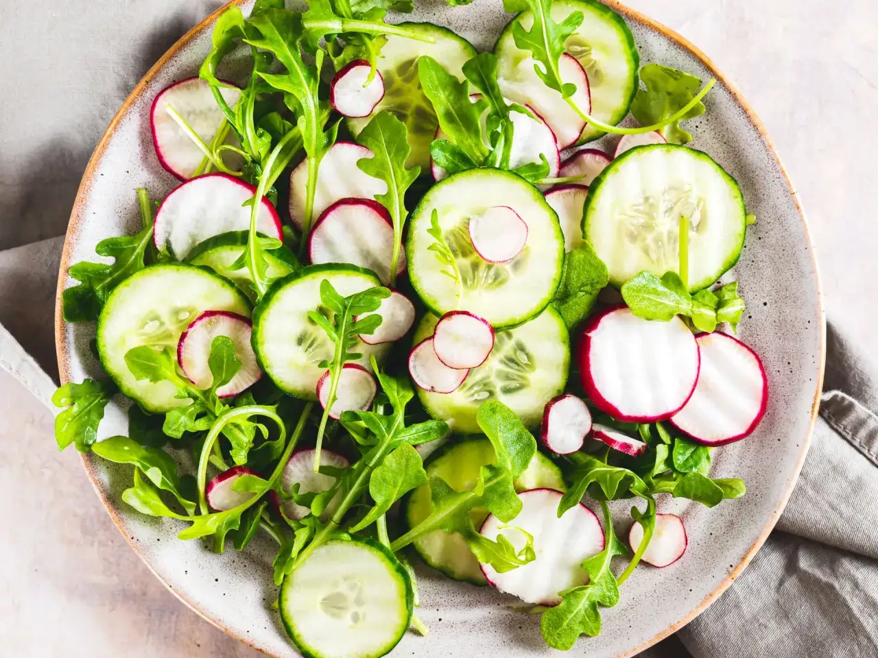 Ensalada fresca con rodajas de pepino, rábano y rúcula. Perfecta para recetas con pepino ligeras y saludables.