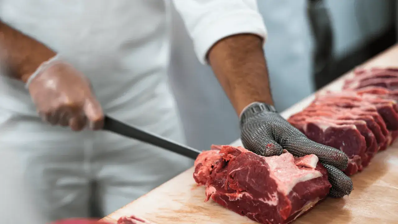 Carnicero prepara carne magra, cortando un trozo fresco con un cuchillo.