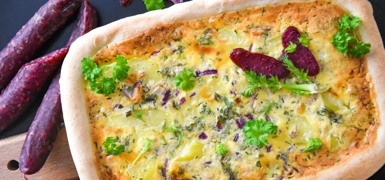 Herzhafte Fenchel-Tarte mit Kartoffeln, roten Zwiebeln und Kr&auml;utern, garniert mit frischer Petersilie und kleinen W&uuml;rsten.