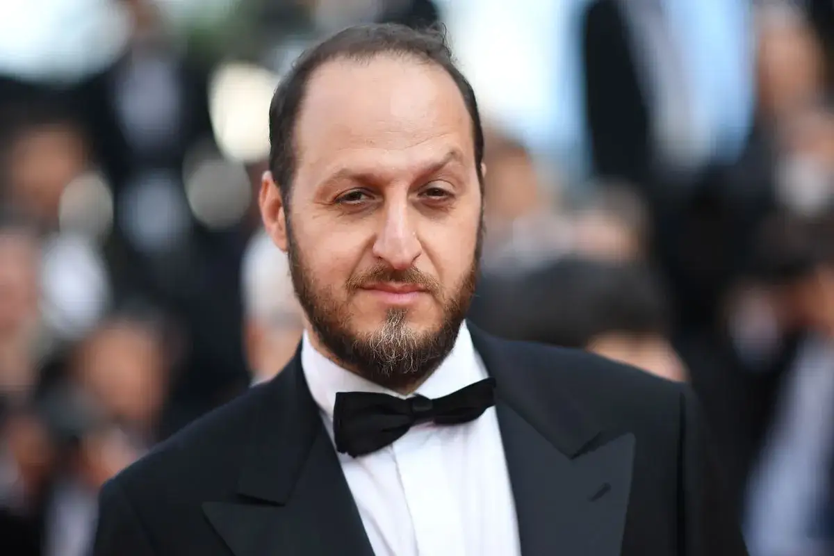 Fausto Russo Alesi, con barba e papillon, in abito elegante su un red carpet.