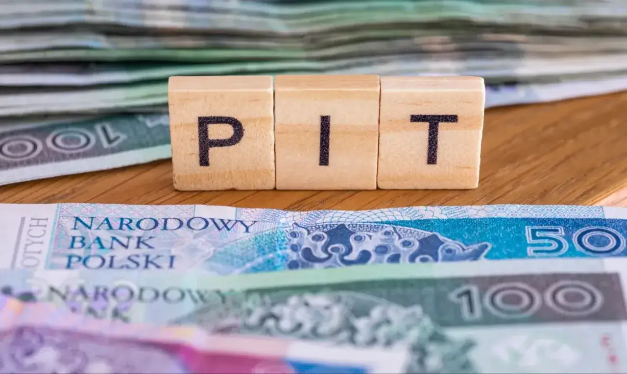 Drewniane klocki z napisem PIT na tle polskich banknotów. Zastanawiasz się, dla kogo PIT 36?