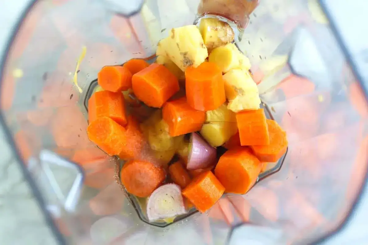 Chopped carrots, pineapple, and ginger are ready to be blended into a vibrant carrot ginger dressing.