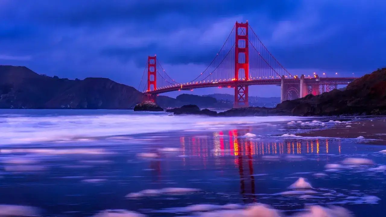 Złota Brama w San Francisco podczas niebieskiej godziny w fotografii. Czerwony most odbija się w spokojnej wodzie, tworząc magiczny widok.