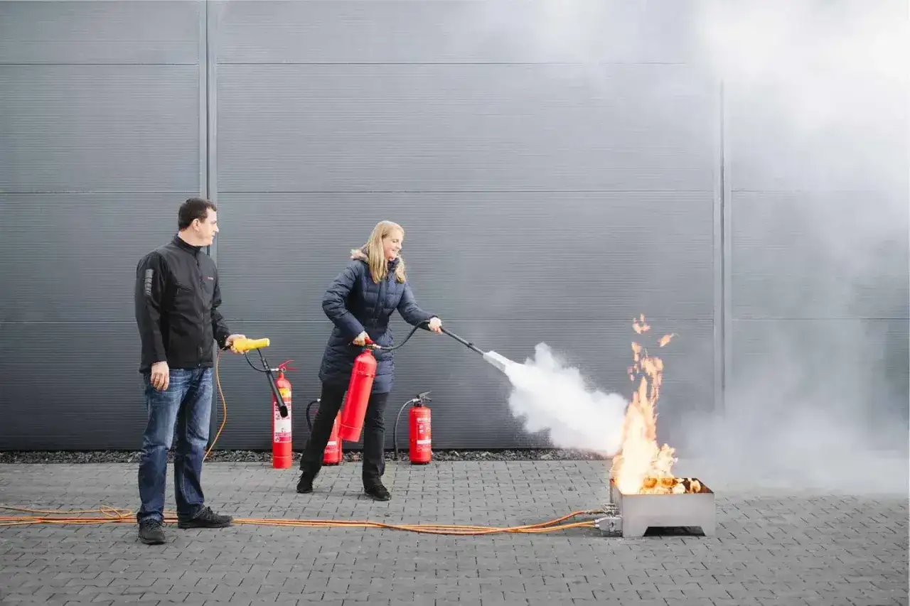Mann und Frau üben den Umgang mit Feuerlöschern. Ein wichtiger Job, der sich im brandschutzhelfer gehalt widerspiegelt.