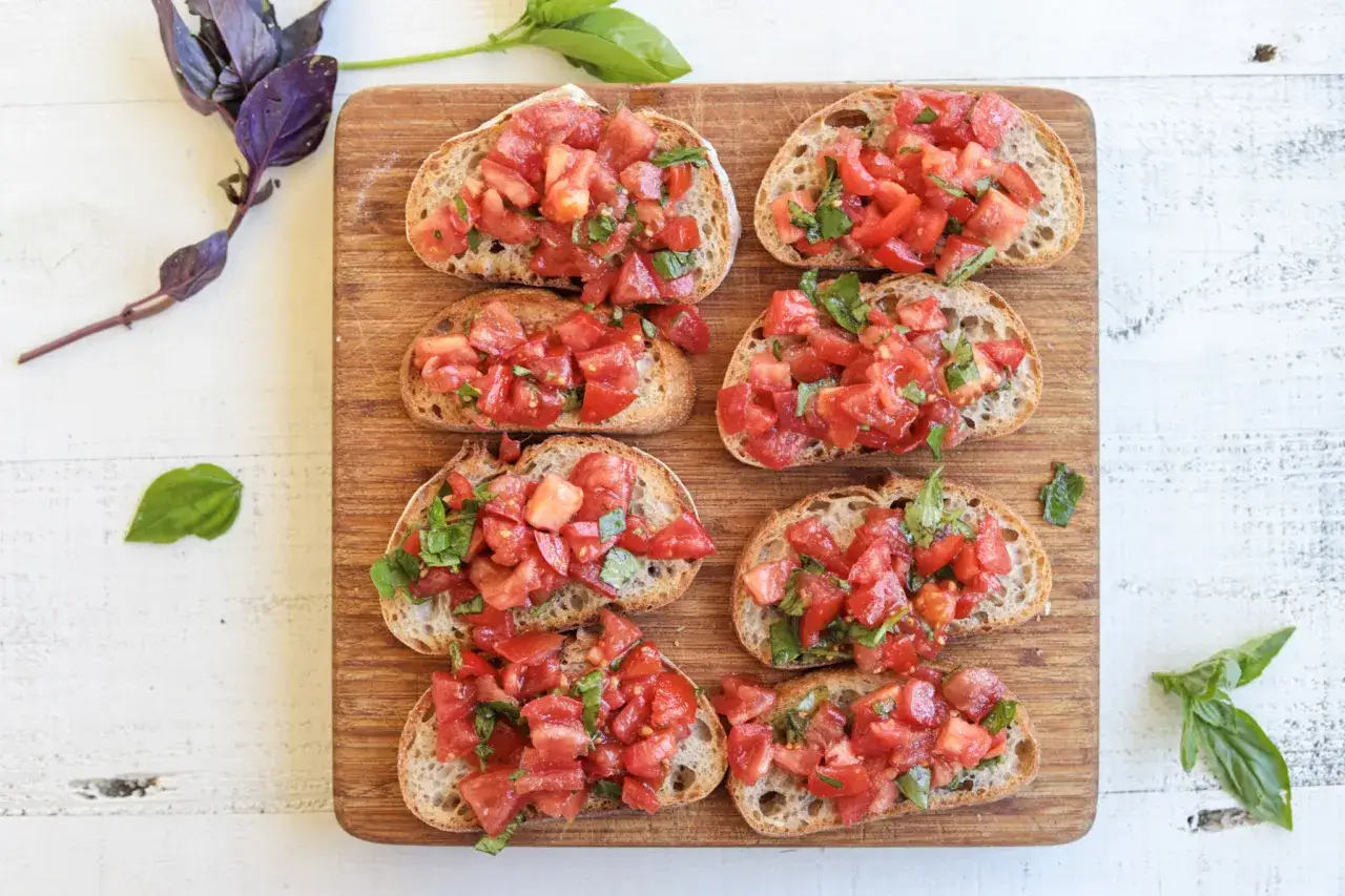 Bruschetta med f&auml;rska tomater och basilika p&aring; en tr&auml;sk&auml;rbr&auml;da. Ett perfekt bruschetta recept f&ouml;r sommaren.