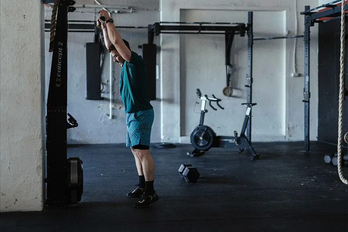 Mężczyzna ćwiczy w siłowni, wykonując ćwiczenie z linką. Zastanawiasz się, crossfit jak często?