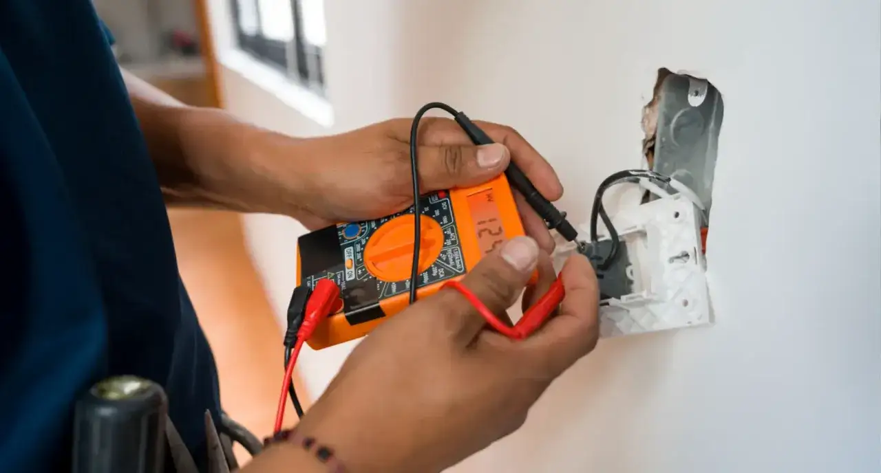 Mani che usano il multimetro per controllare un impianto elettrico.