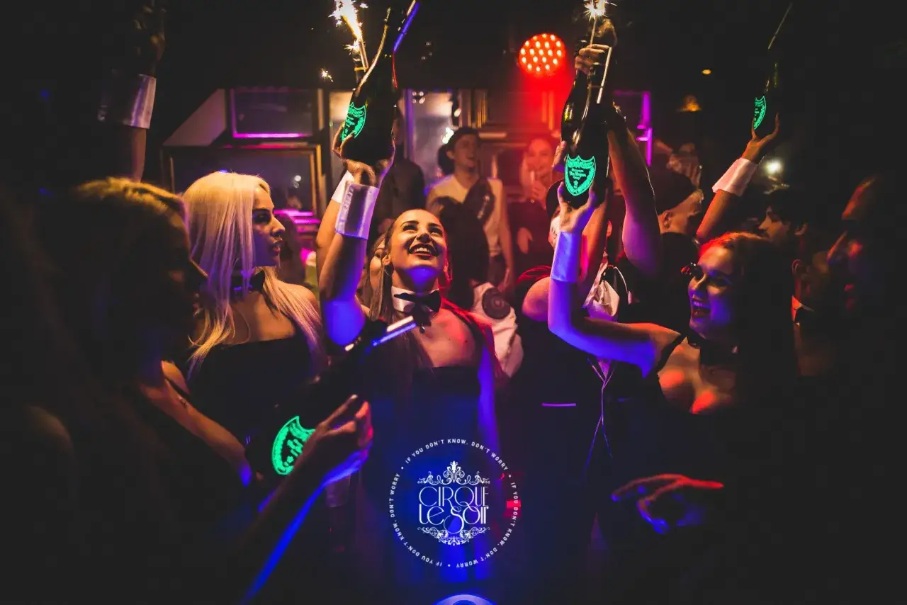 Festa a Londra, gente felice con bottiglie di champagne illuminate e scintille. La vita notturna londinese &egrave; vibrante!
