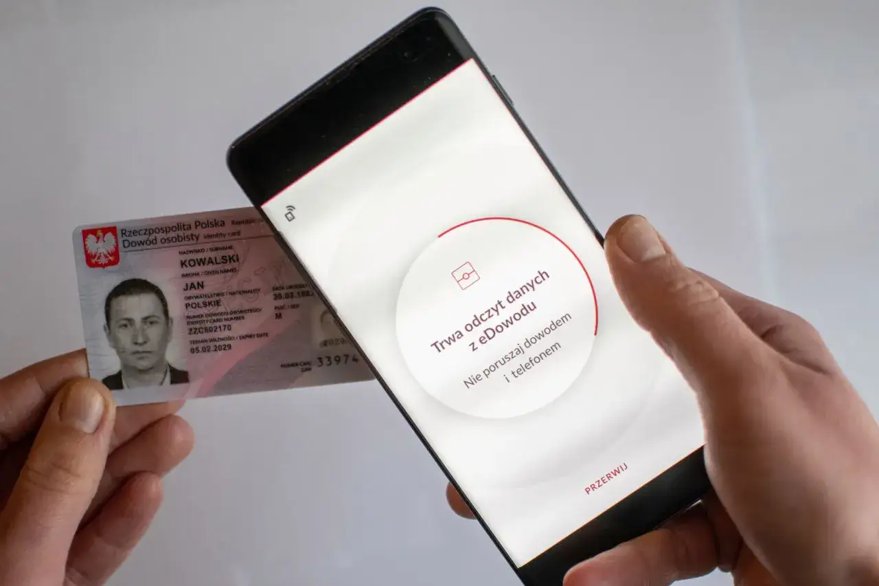 Ręce trzymają dowód osobisty i smartfon z komunikatem 