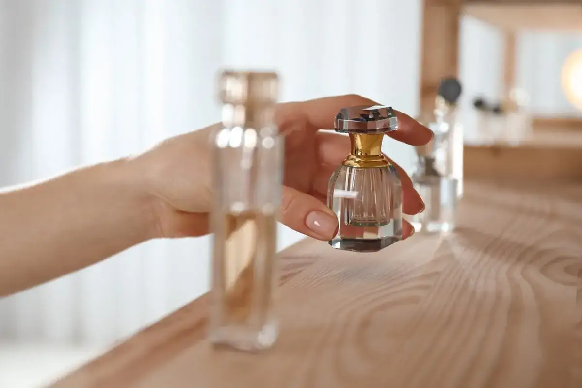 Dłoń trzyma elegancką, kryształową buteleczkę perfum. Proces maceracji perfum pozwala na pełne rozwinięcie ich zapachu.