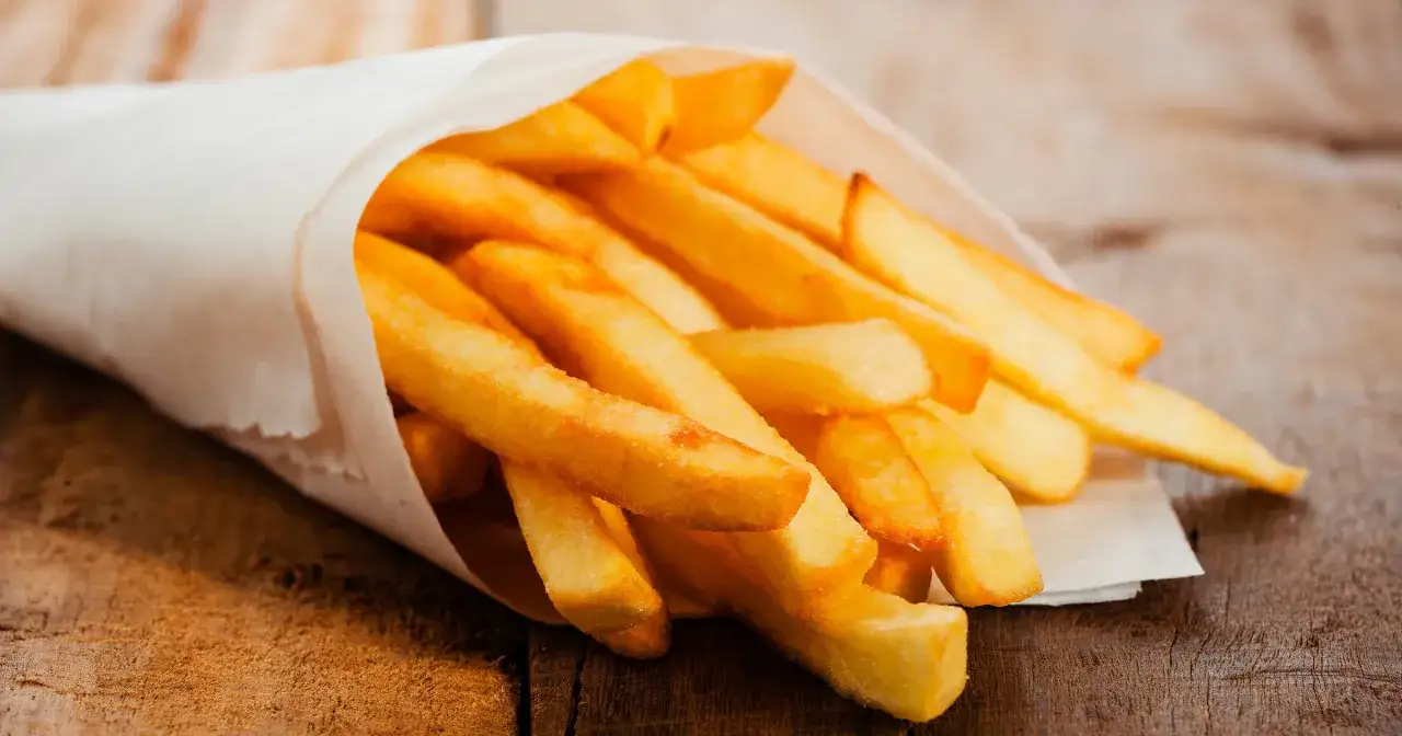 Złociste frytki w papierowym rożku, idealne na zasłużony cheat meal.