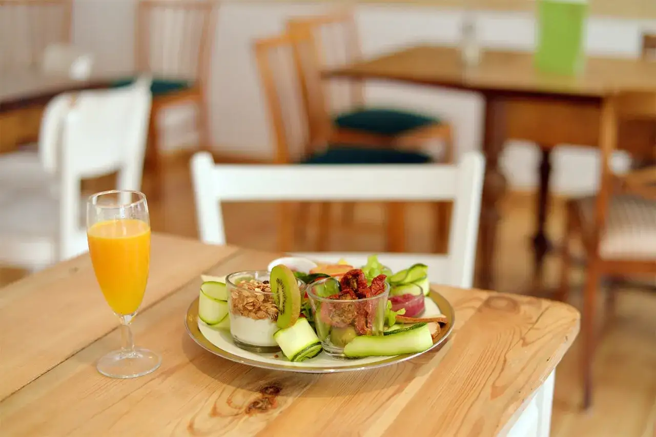 Leckeres vegan breakfast in Berlin: Joghurt mit M&uuml;sli, Kiwi, Gurke, Tomaten und Orangensaft.