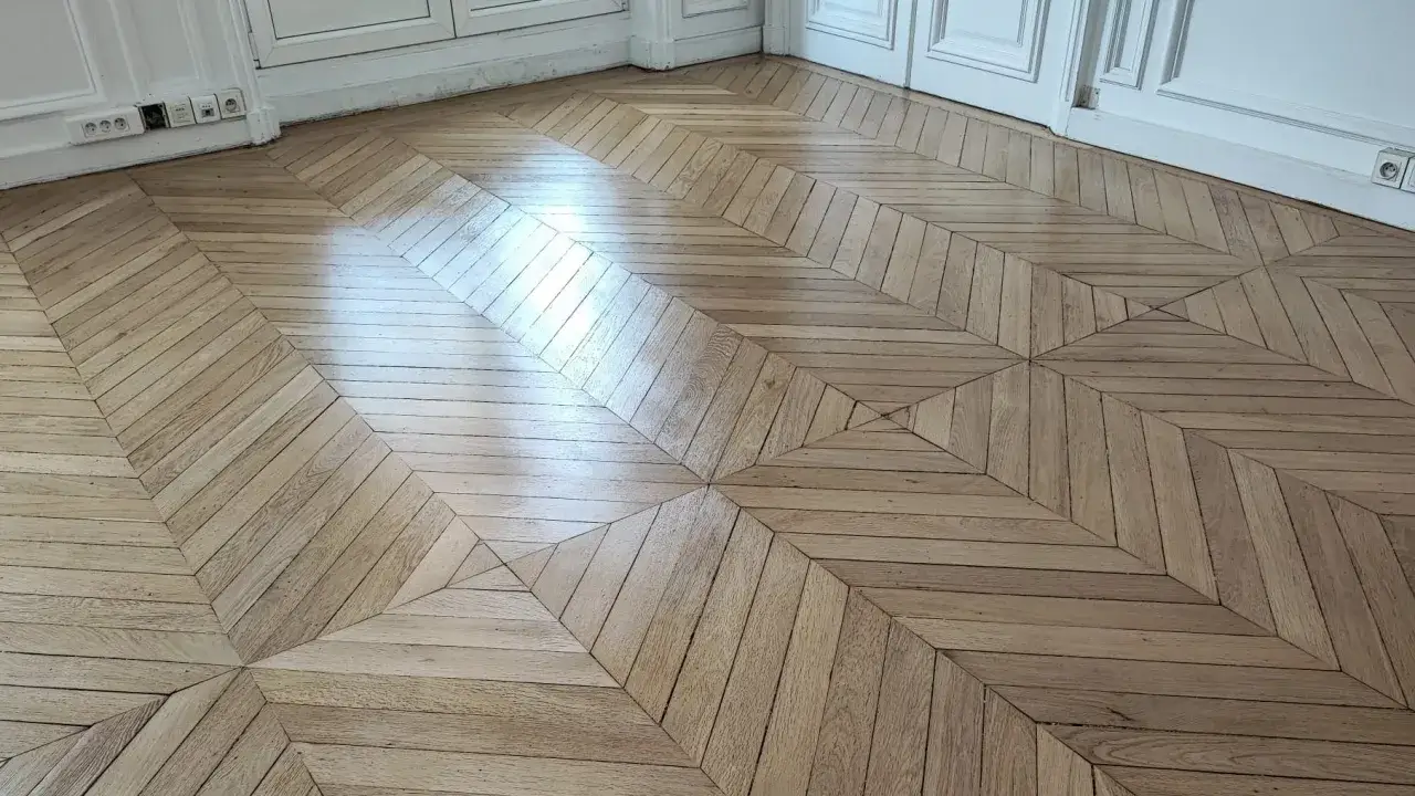 Parquet ancien en bois clair, motif g&eacute;om&eacute;trique en losanges et chevrons. Une r&eacute;novation qui redonne vie &agrave; ce sol d'exception.
