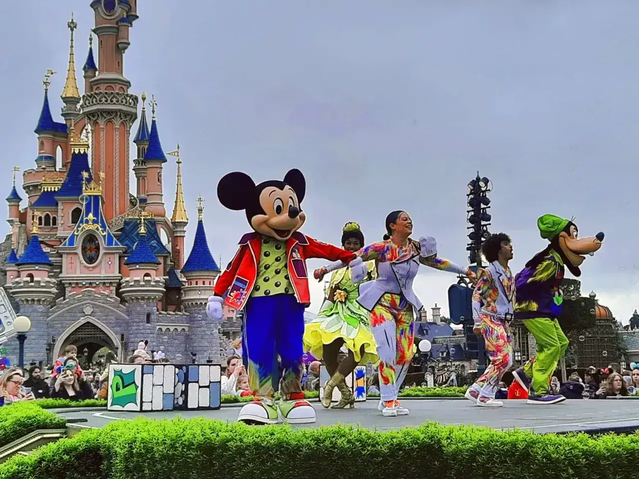 Myszka Miki i przyjaciele tańczą na scenie przed zamkiem w Disneylandzie.