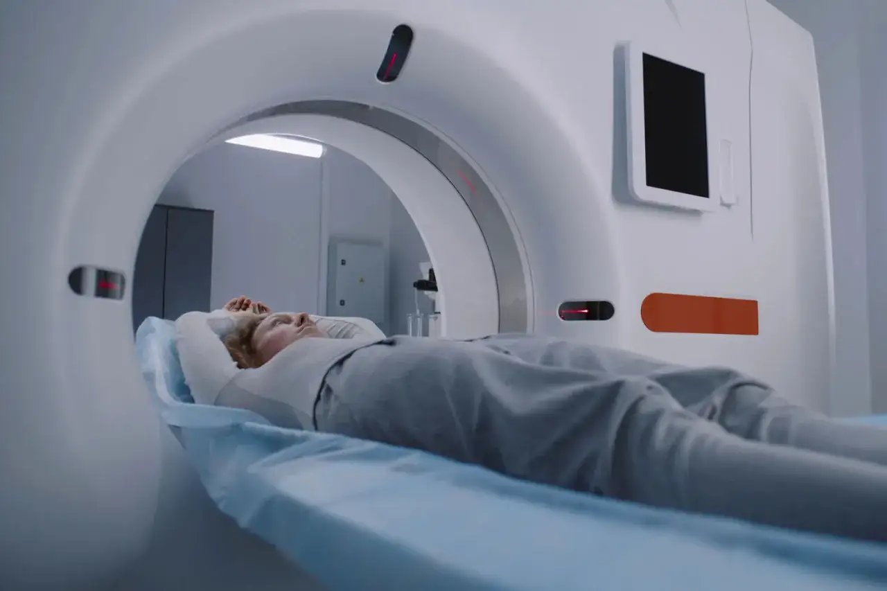Pacjentka leży na stole do rezonansu magnetycznego, przygotowując się do badania. Widok pokazuje wnętrze aparatu, jak wygląda rezonans magnetyczny piersiowy.