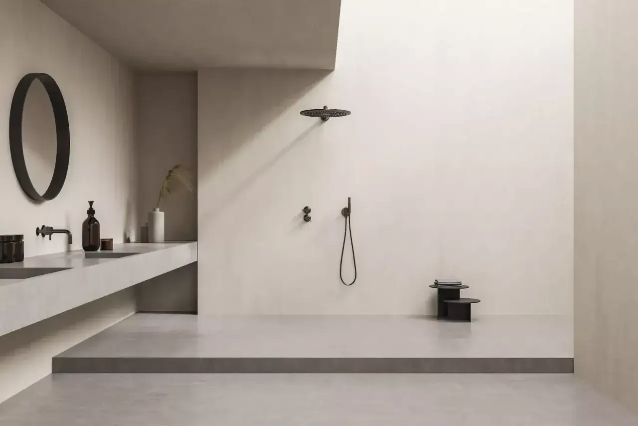 Minimalistisches Bad mit offener Dusche. Die bodentiefe Dusche ist so gestaltet, dass Spritzwasser vermieden wird. Ein schwebendes Waschbecken mit Spiegel und ein kleiner Beistelltisch ergänzen den Raum.