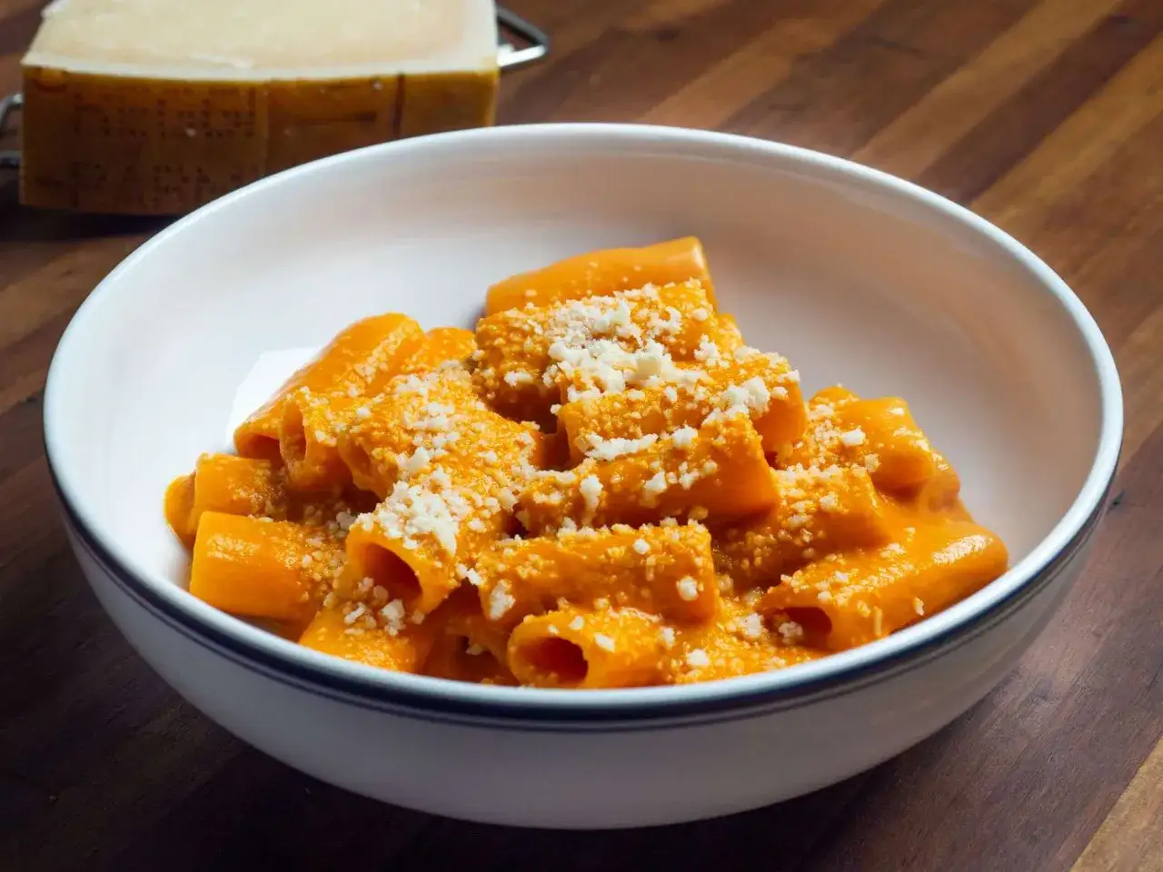 En skål med rigatoni i krämig tomatsås, toppad med riven ost. En klassisk vodka pasta som ser utsökt ut.