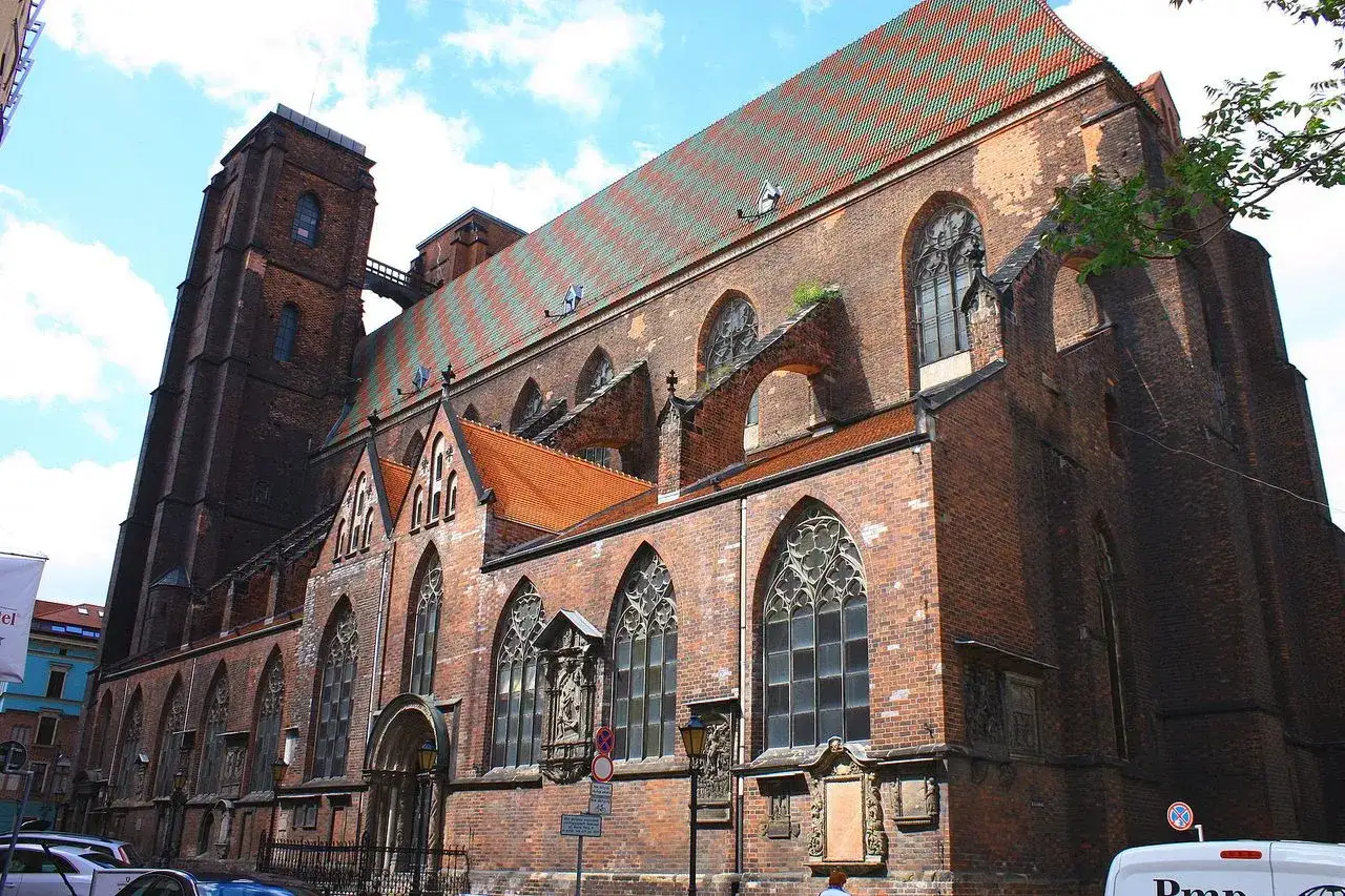 Gotische Backsteinkirchen in Breslau mit markantem, bunt gedecktem Dach und einem hohen Turm.