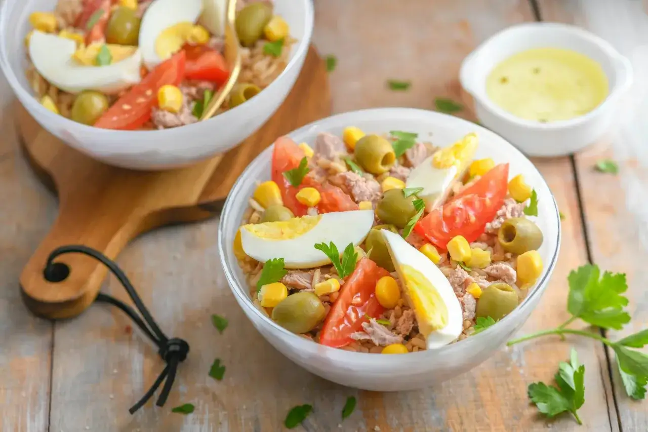 Salade de riz ni&ccedil;oise app&eacute;tissante avec thon, &oelig;ufs durs, tomates, olives et ma&iuml;s. Un d&eacute;lice estival.