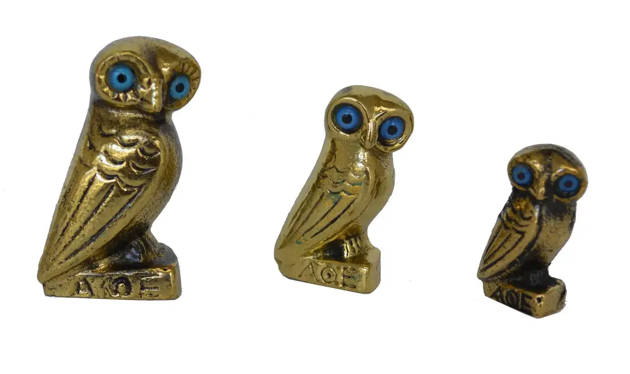 Trois statuettes de chouettes dor&eacute;es, symboles d'Ath&eacute;na, avec des yeux bleus vifs. L'inscription 