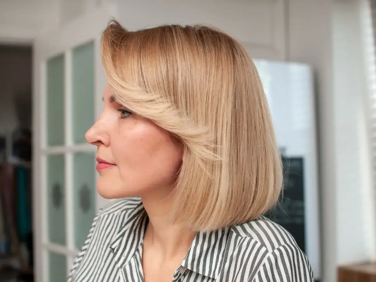 Kobieta z blond włosami do połowy szyi z grzywką, w paski.