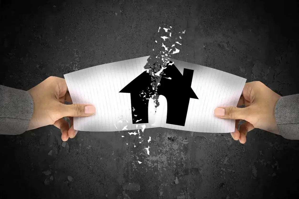 Deux mains déchirent un papier représentant une maison, symbolisant la lutte pour se défendre contre une accusation de vice caché maison.