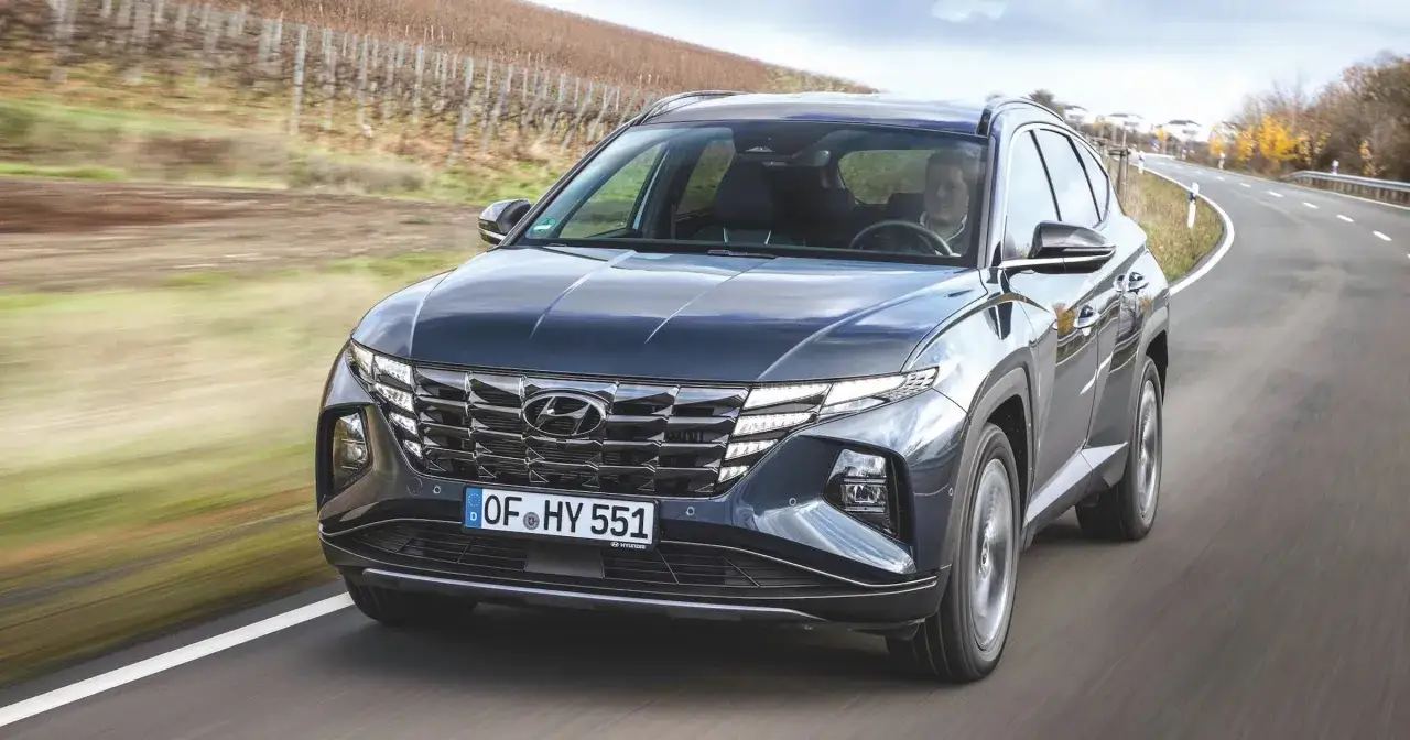 Ciemnoszary Hyundai Tucson hybryda jedzie po krętej drodze wśród winnic.
