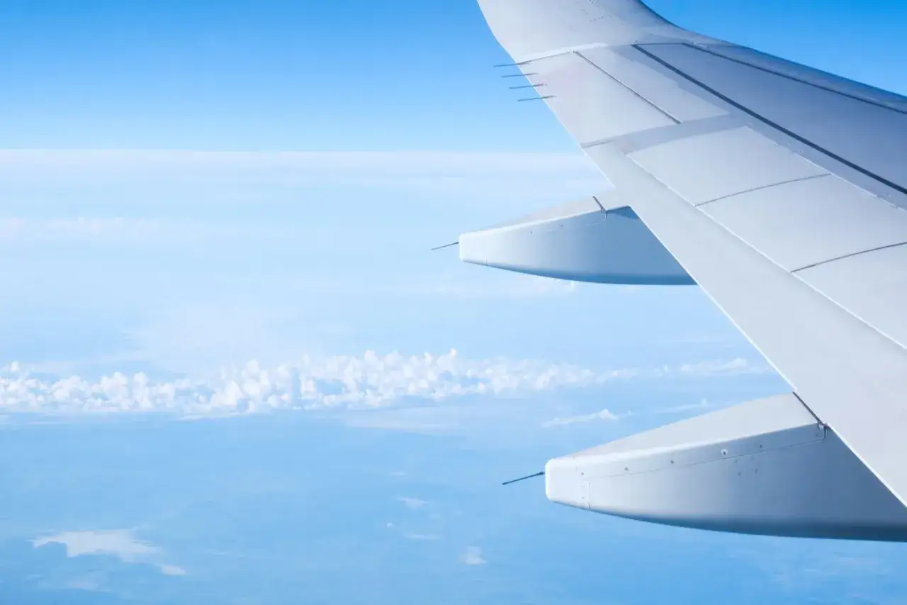 Flügel eines Flugzeugs über den Wolken. Die linienflug geschwindigkeit lässt die Welt unter uns wie ein Gemälde aussehen.