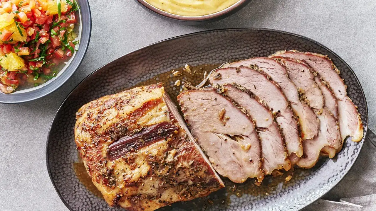 Rôti de porc au lait, tranché et servi avec une sauce savoureuse, accompagné d'une salade de tomates et d'agrumes.