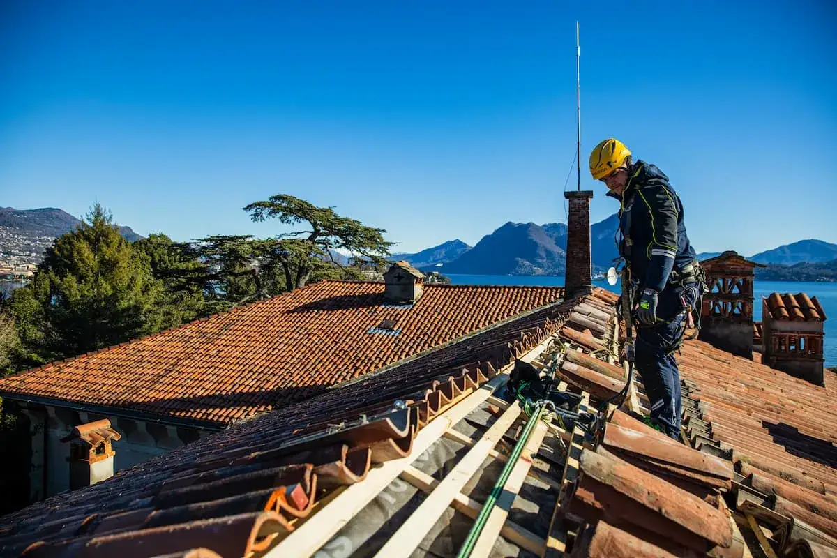 Operaio in azione per la realizzazione tetti in legno, con vista lago e montagne.