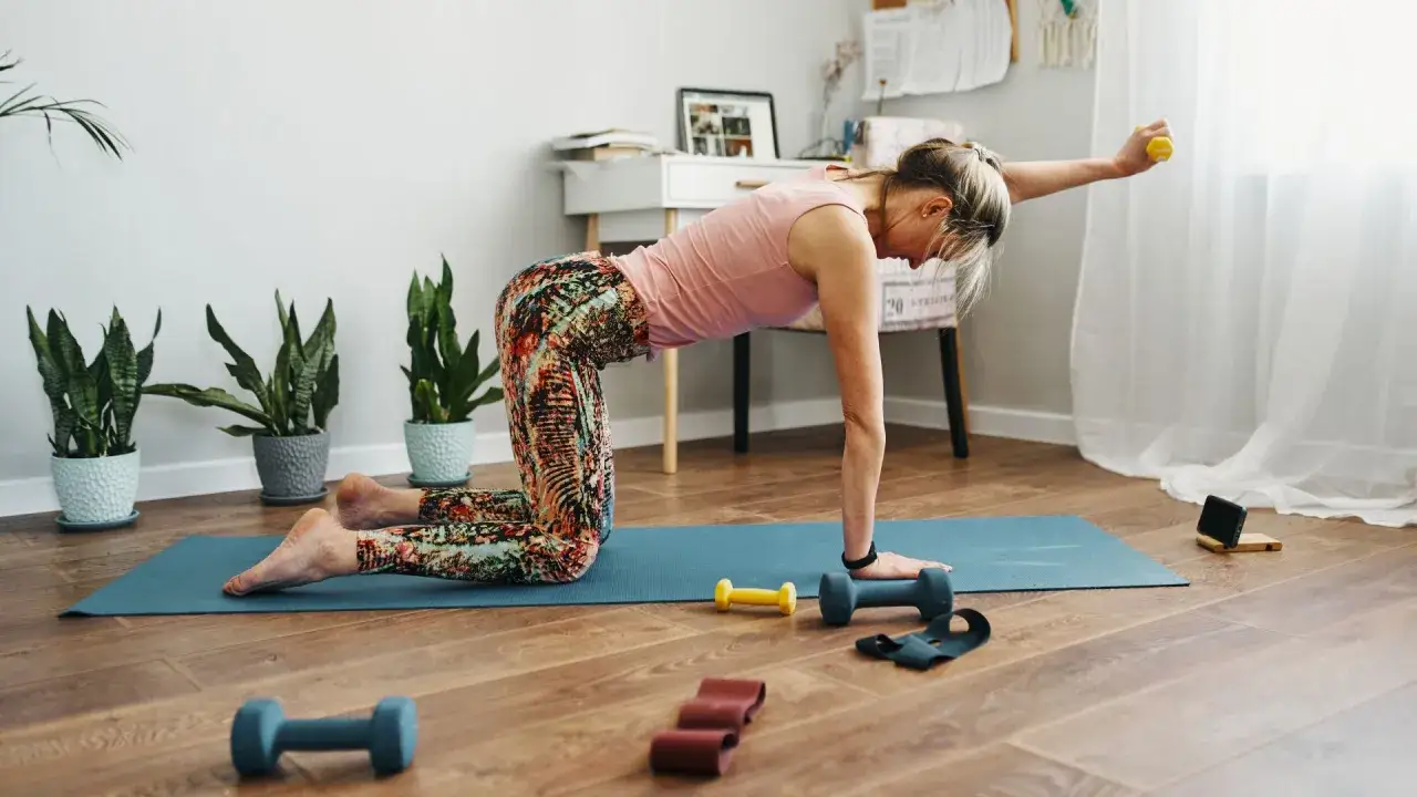 Donna in posa yoga con pesi e bande elastiche, un allenamento che dimostra come il pilates fa dimagrire tonificando il corpo.