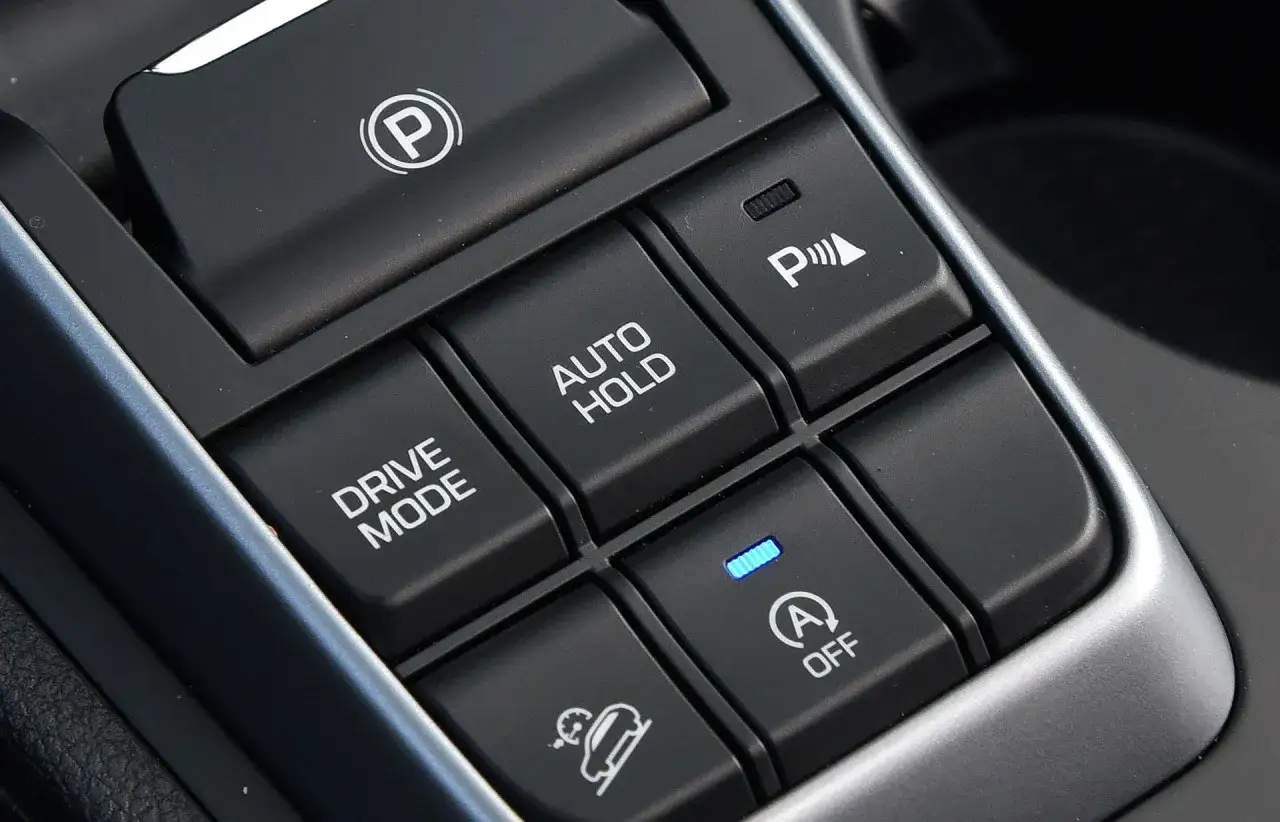 Przyciski w samochodzie: hamulec postojowy, Drive Mode, Auto Hold, asystent parkowania i kontrola zjazdu ze wzniesienia. Hill holder ułatwia ruszanie pod górę.