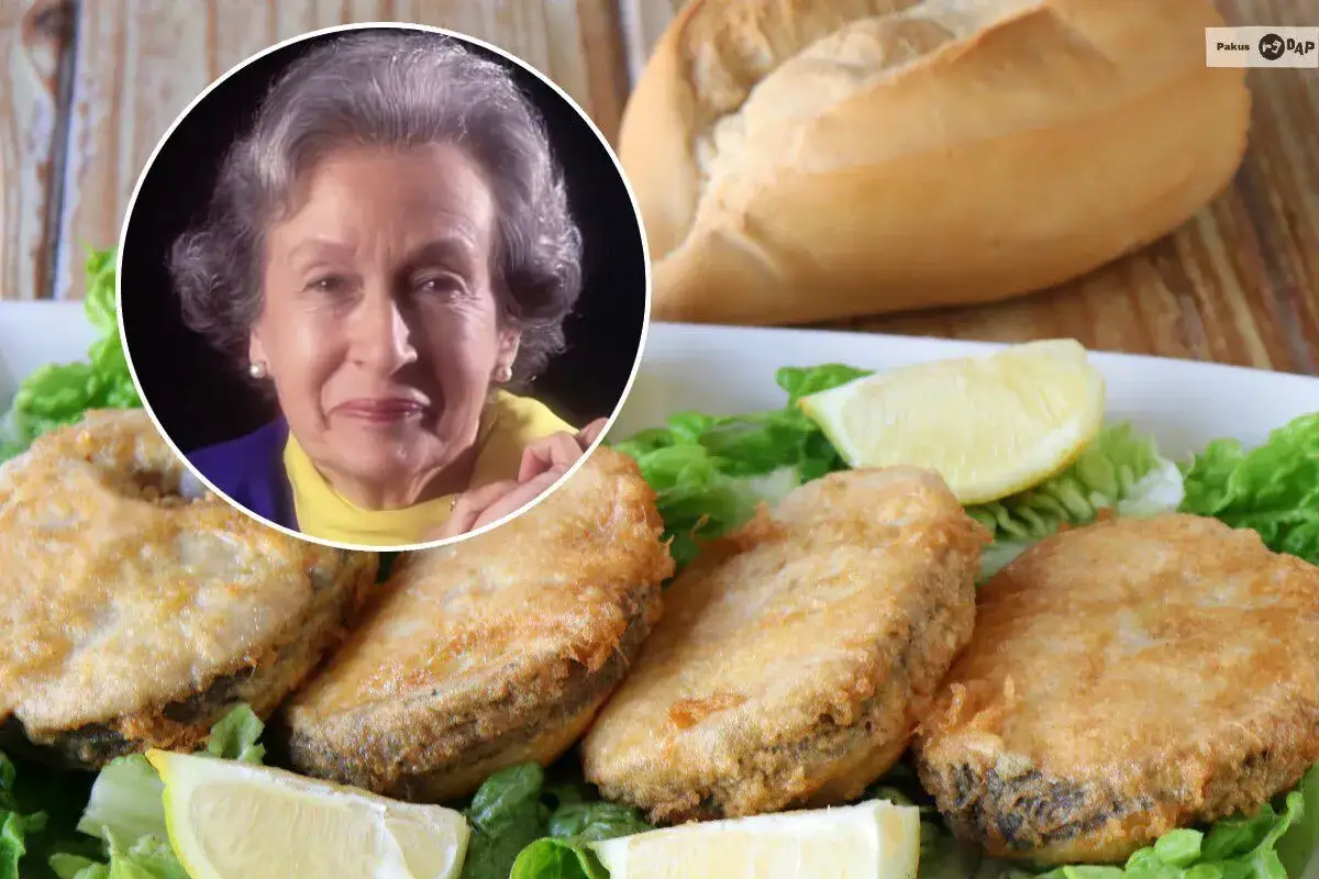 Mujer sonr&iacute;e junto a plato de merluza a la romana, con lechuga y lim&oacute;n.