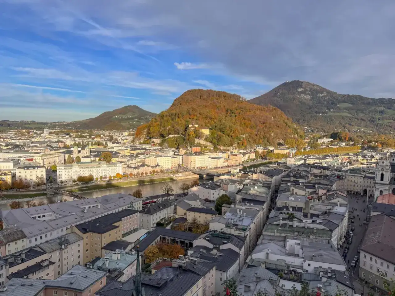 Blick &uuml;ber Salzburg mit der Salzach und den Bergen im Herbst. Entdecken Sie die verborgenen Salzburg Geheimtipps abseits der Touristenpfade.