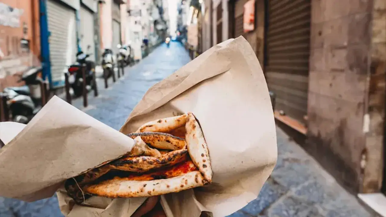 Pizza a portafoglio, un classico cibo napoli, gustata passeggiando tra i vicoli.