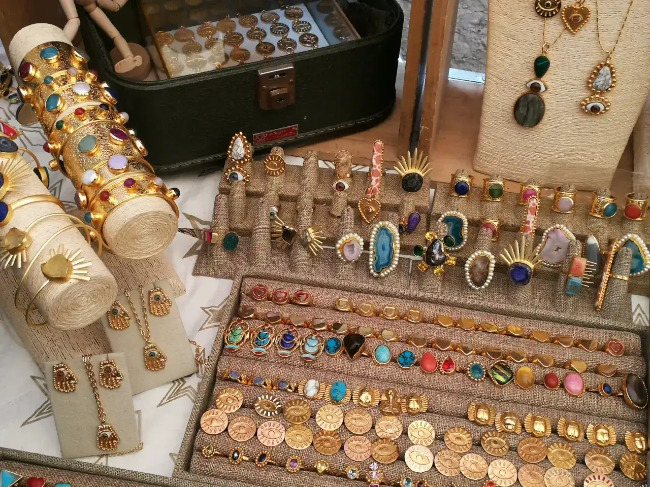 Exhibición de pulseras, anillos y collares dorados con piedras semipreciosas, un ejemplo de la **fabricación de joyas** artesanal.