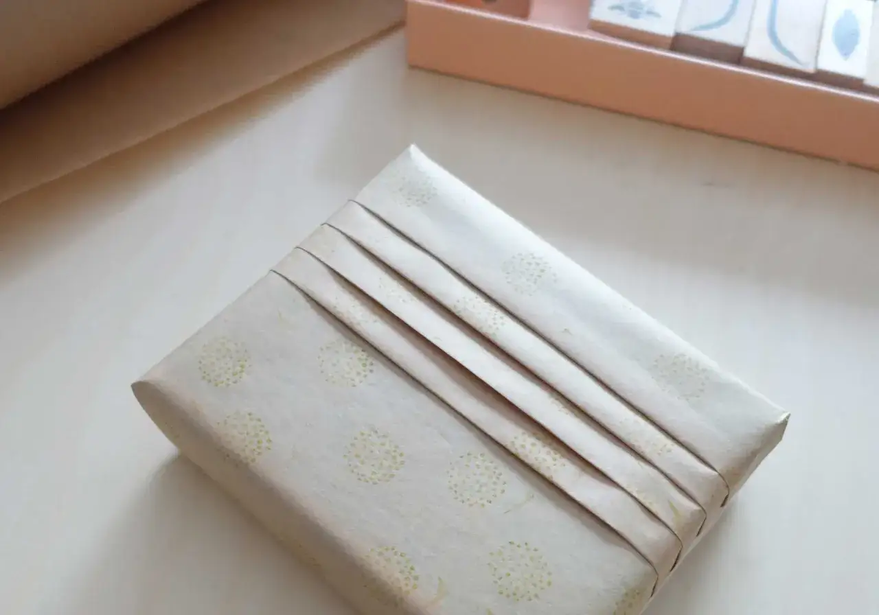 Ett paket inslaget i papper med prickm&ouml;nster, fint dekorerat med veck.