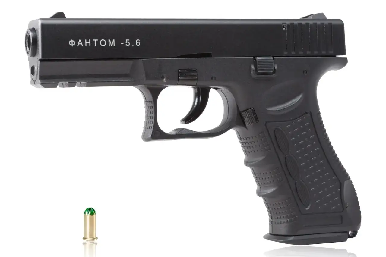 Czarny pistolet hukowy 6mm Czechy, model Phantom, obok naboju.