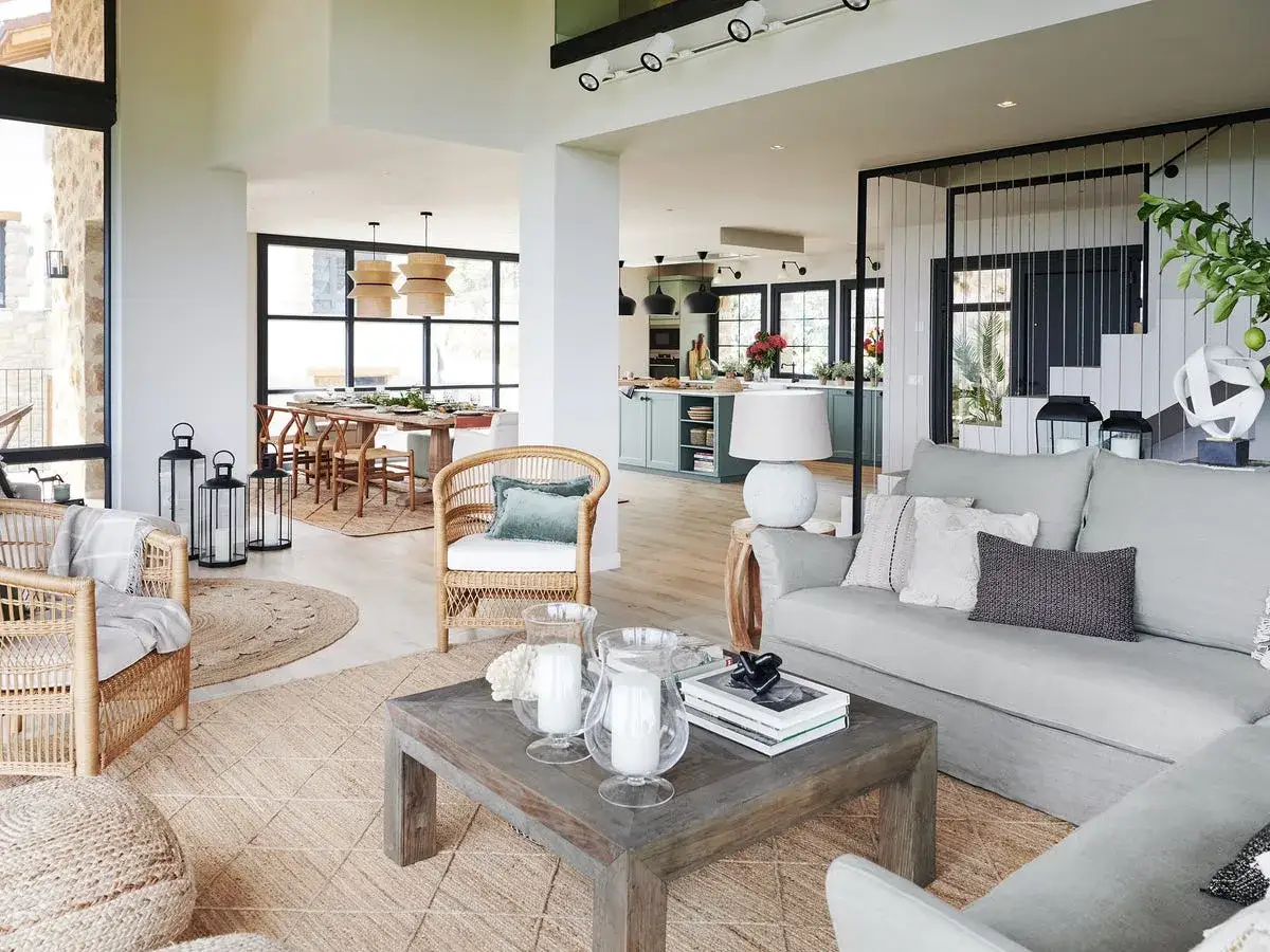 Ideas para decorar casa de campo con poco dinero: sillones de mimbre, alfombras de yute y detalles rústicos crean un ambiente acogedor.