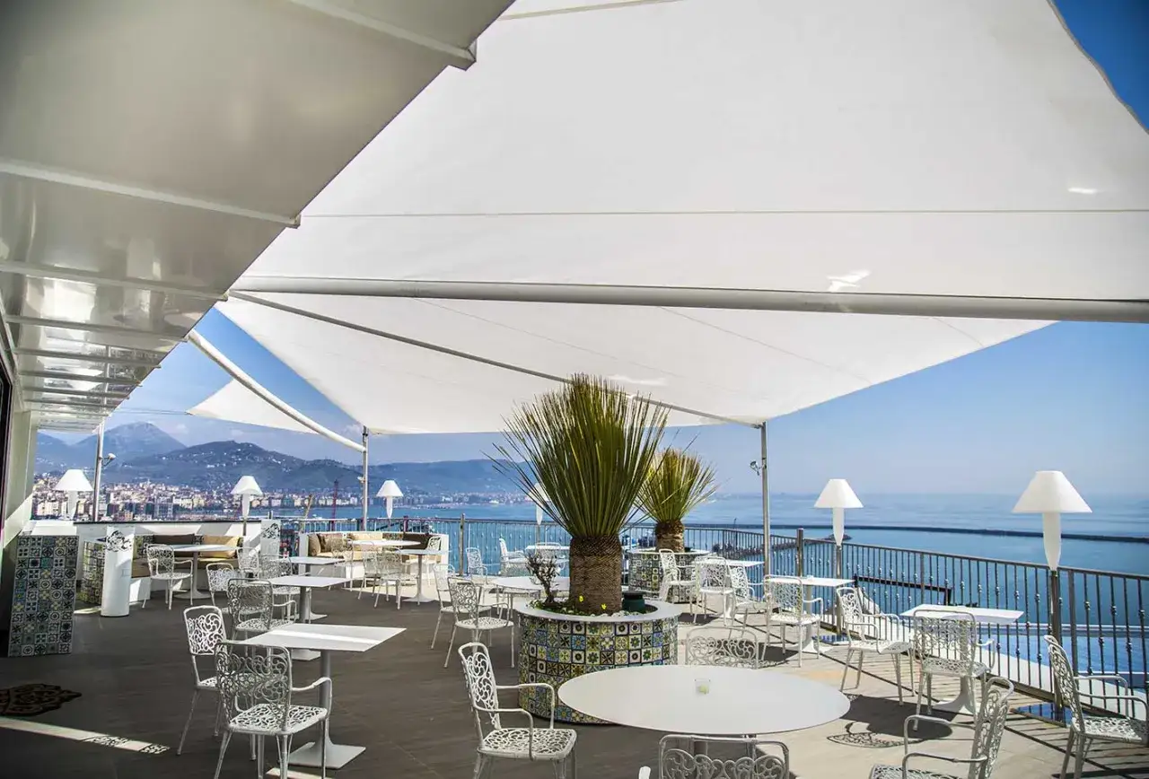 Terrazza panoramica con tavoli e sedie bianche, ideale per godersi la vista mozzafiato dei ristoranti sul mare a Salerno.