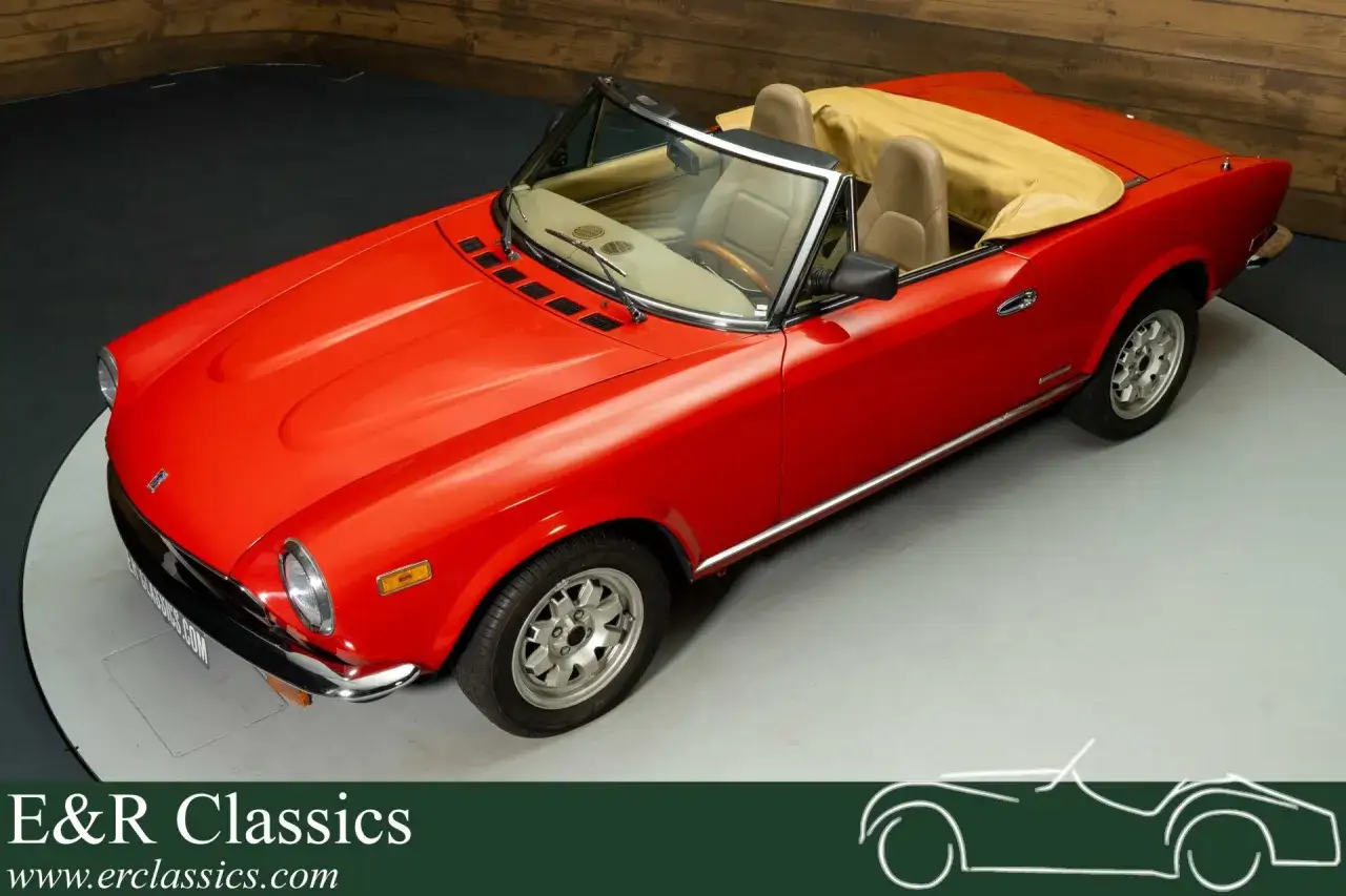 R&ouml;d Fiat 124 Spider till salu, en klassisk cabriolet med beige inredning och sufflett. Perfekt f&ouml;r sommarens k&ouml;rningar.