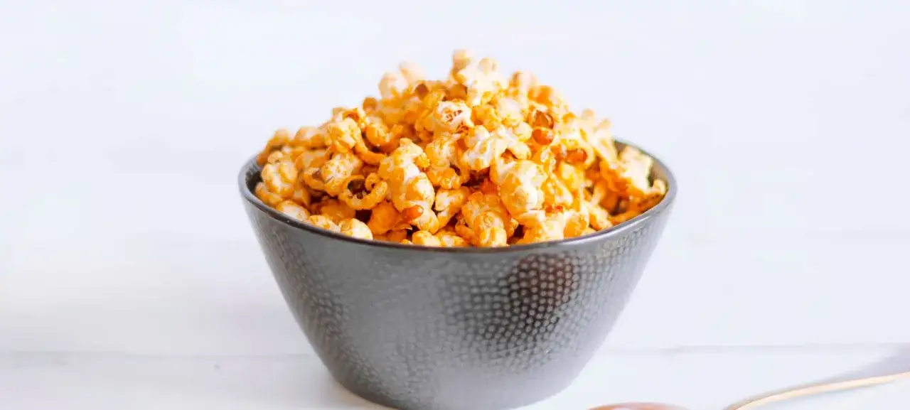 Chrupiący popcorn w karmelu, przygotowany w frytkownicy beztłuszczowej, w ciemnej misce. Idealna przekąska!