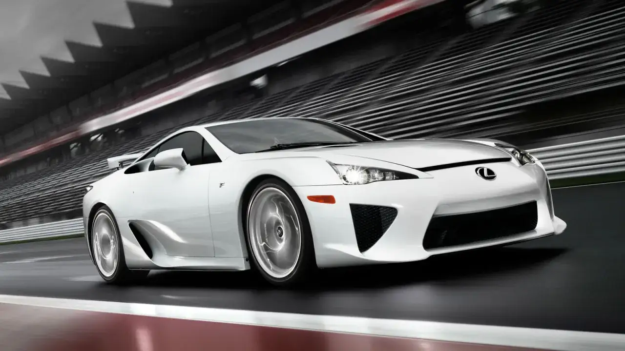 Biały Lexus LFA pędzi po torze wyścigowym, jego felgi wirują w rozmyciu prędkości.