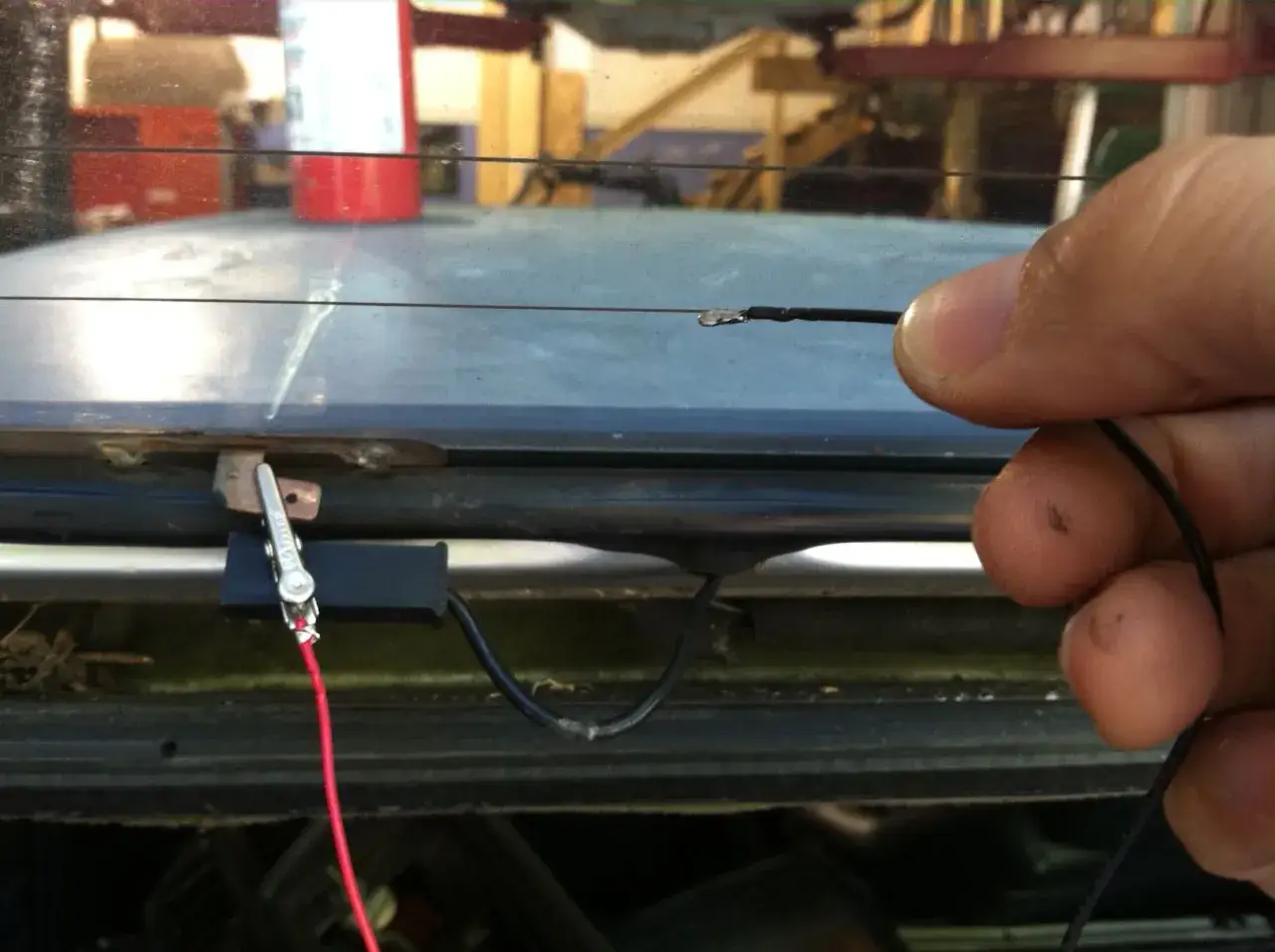 Reparación de los filamentos transversales de la luneta trasera. Un cable negro se conecta a uno de ellos.