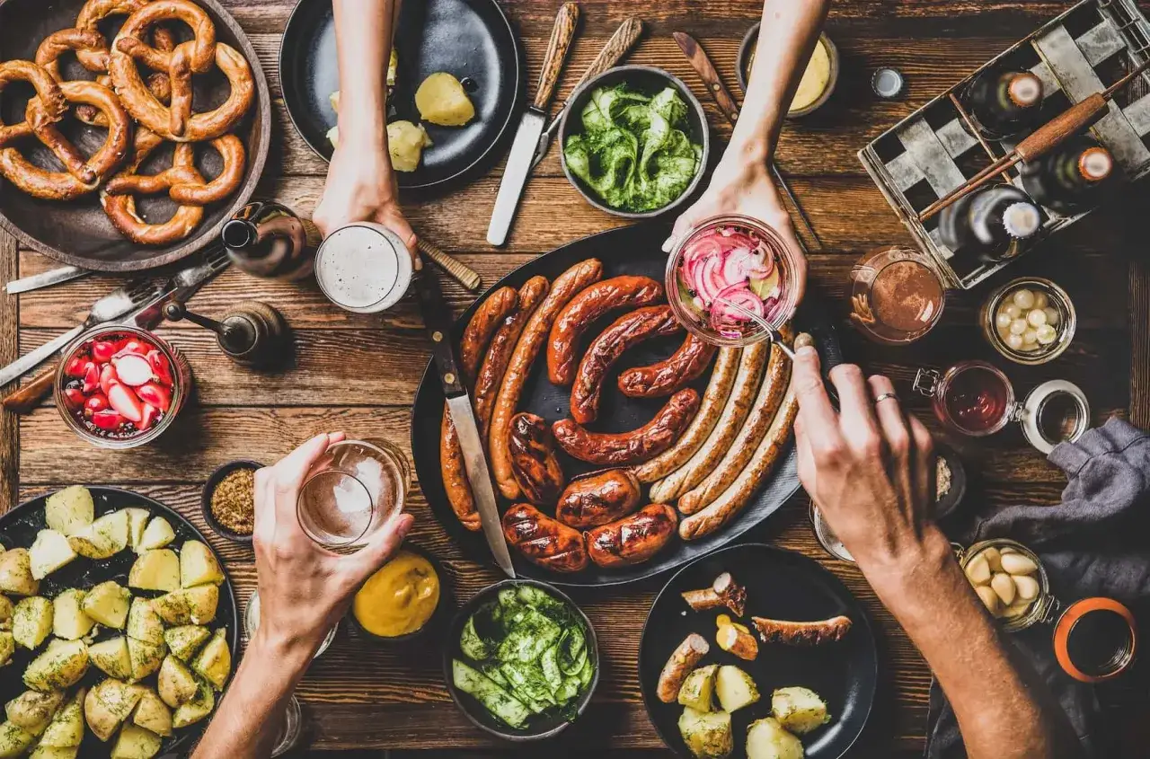 Herzhaftes deutsches Essen: Bratwürste, Kartoffeln, Brezeln und Bier laden zum Genießen ein.