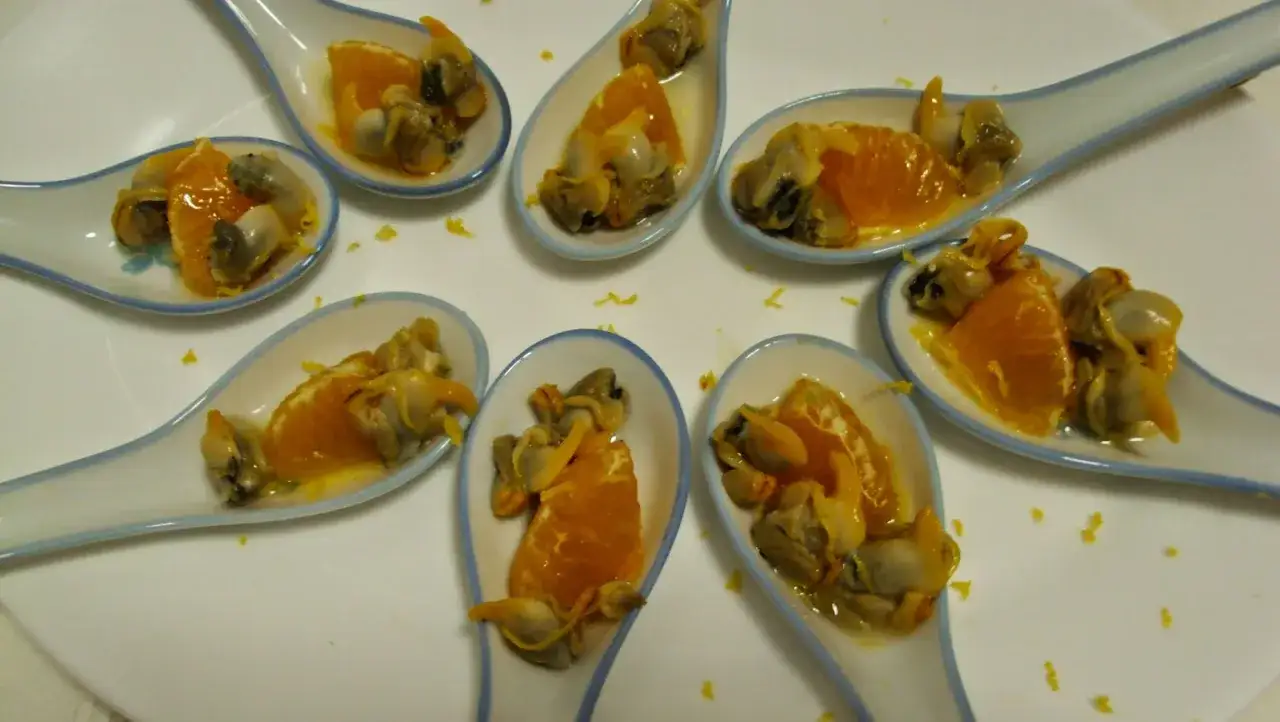 Cucharitas con ceviche de berberechos y gajos de naranja, un bocado fresco y cítrico.